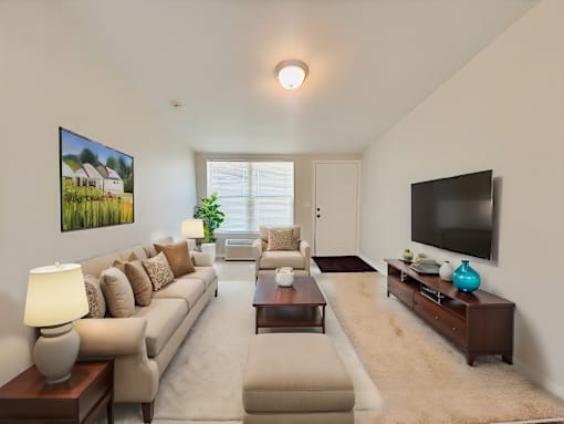 A living room with a beige sofa, a coffee table, and a flat screen TV.
