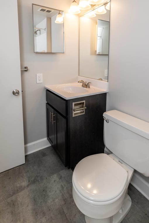 Bathroom with a toilet sink and mirror at McDonogh Village Apartments & Townhomes, Randallstown