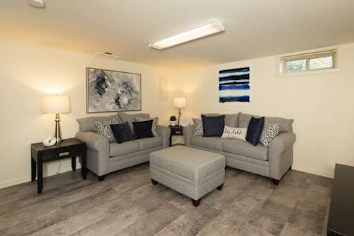 Basement with hardwood, vinyl flooring with couches and ottoman