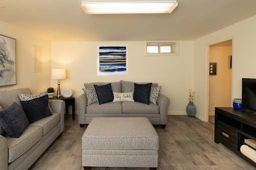 Basement with hardwood, vinyl flooring with couches and ottoman