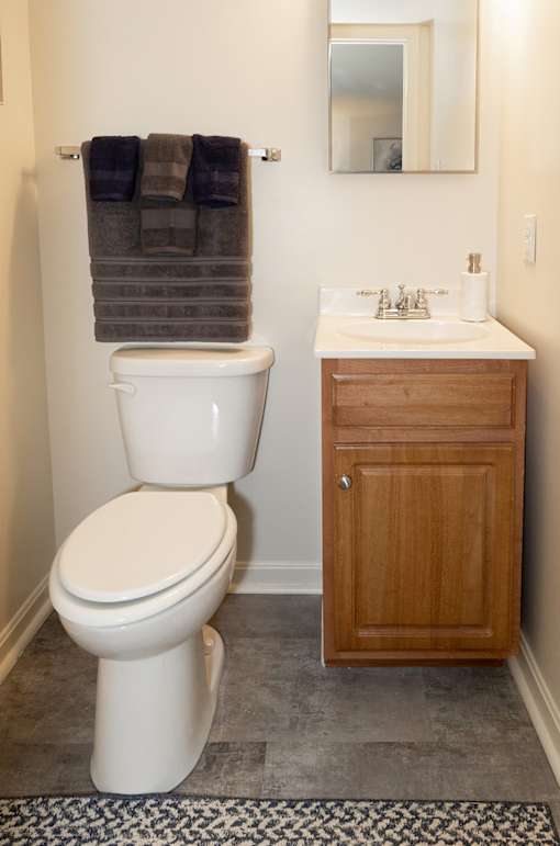 A white toilet sits next to a sink in a bathroom at Walnut Grove Townhomes* Apartments, Essex, MD