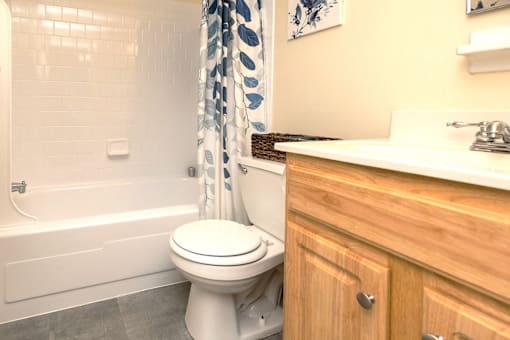 A white toilet sits next to a bathtub in a bathroom at Kingston Townhomes, Baltimore, MD