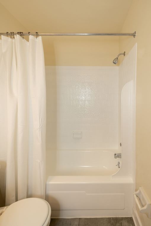 A white toilet sits next to a white bathtub in a bathroom.