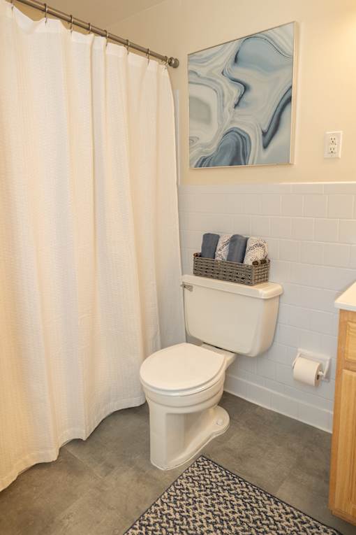 A white toilet in a bathroom with a shower curtain.
