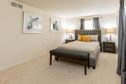 A bedroom with a large bed and two framed pictures on the wall.