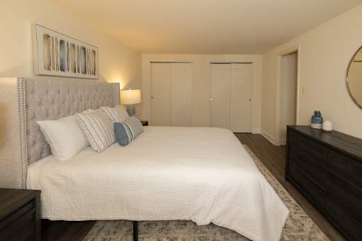 A bedroom with a large bed, a dresser, and a mirror.