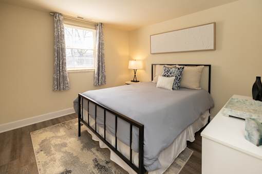 A bedroom with a bed, nightstand, and window.