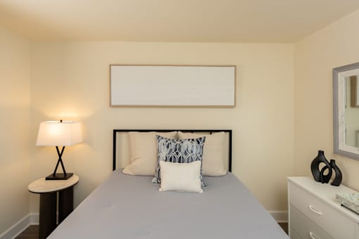 A bedroom with a bed, nightstand, lamp, and a blanket.