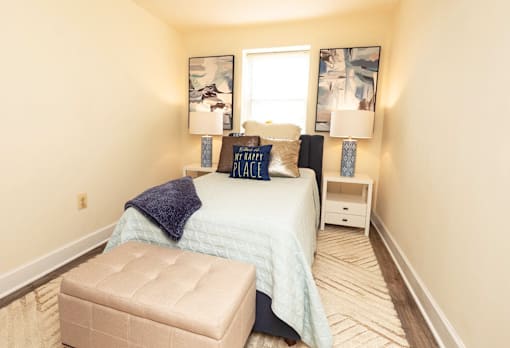 A bedroom with a bed, nightstand, and chair.