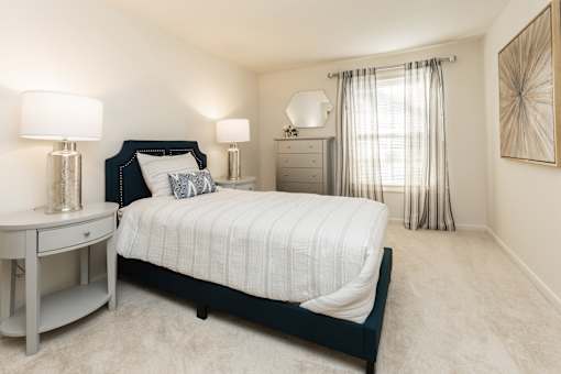 A bedroom with a large bed, a nightstand, and a dresser.