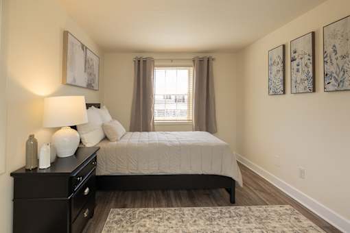 A bedroom with a bed, nightstand, and pictures on the wall.