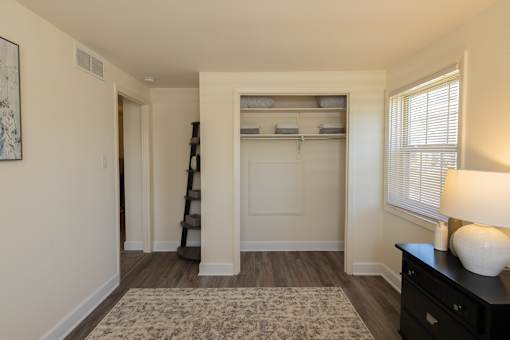 A room with a ladder and a dresser with a lamp on it.