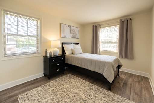 A bedroom with a bed, nightstand, and window