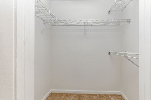 Empty walk-in closet with white walls and shelving.