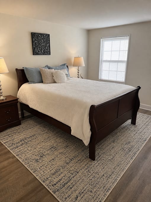 A bedroom with a large bed and a patterned rug.