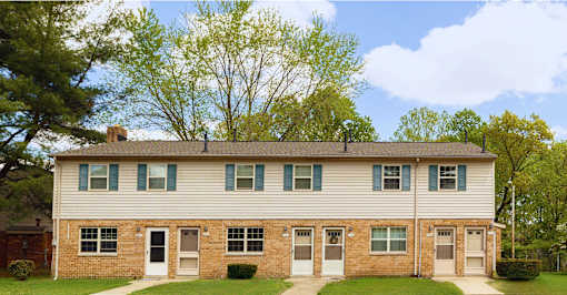 A two-story house with a white front and a brick base.at Severn Townhomes*, Severn, MD 21144