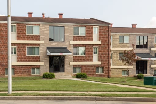 A red brick apartment building with a green lawn in front at Winston Apartments, Baltimore, Maryland