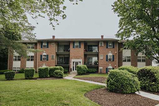 A brick building with green bushes in front at Deer Park Apartments, Randallstown, 21133