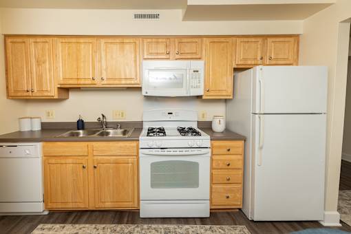 A kitchen with wooden cabinets and white appliances at The Brittany Apartments, Pikesville, MD, 21208