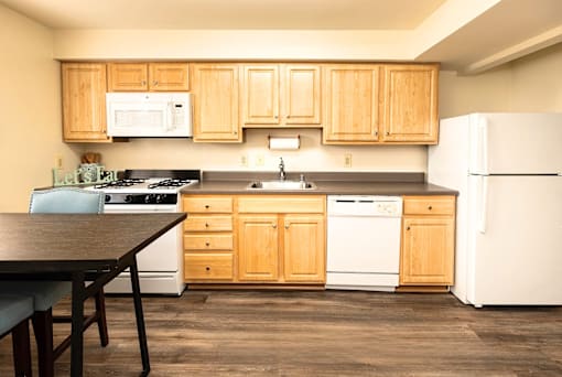 A kitchen with wooden cabinets and white appliances at Kingston Townhomes, Baltimore, MD