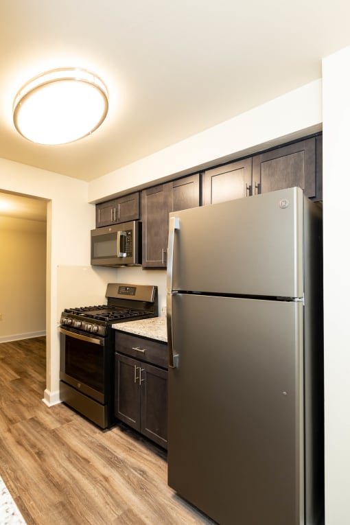 a kitchen with dark wood cabinets and stainless steel appliances at Seminary Roundtop Apartments, Lutherville, MD, 21093