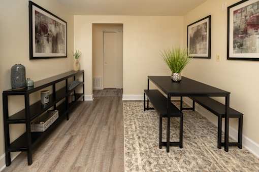 A black table with a plant on it sits in the middle of a room with a wooden floor and a carpet.