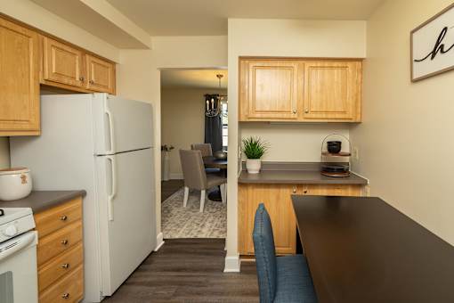 A kitchen with a refrigerator, stove, and wooden cabinets at The Brittany Apartments, Pikesville