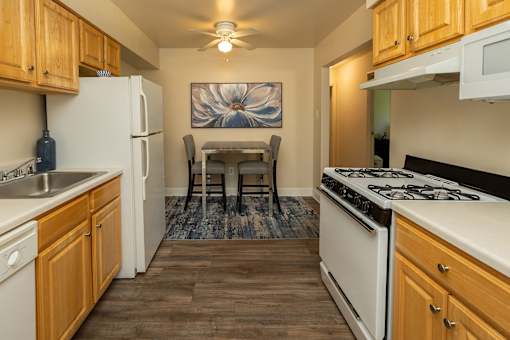 A kitchen with wooden cabinets and a white stove top oven.at Deer Park Apartments, Maryland, 21133