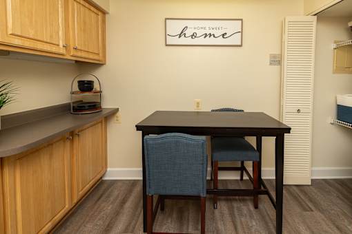 A kitchen with a table and chairs and a sign on the wall at The Brittany Apartments, Maryland
