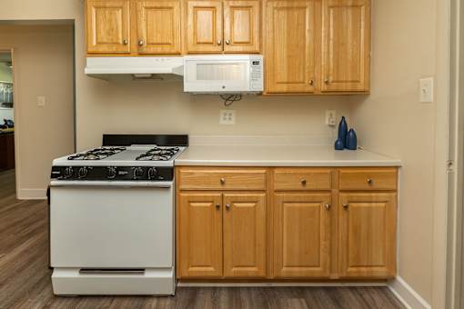 A kitchen with wooden cabinets and a white stove.at Deer Park Apartments, Maryland