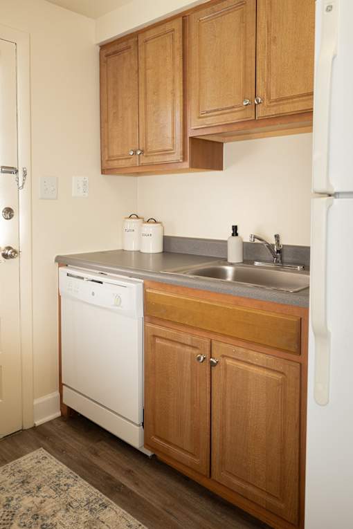 A white dishwasher is in a kitchen with wooden cabinets