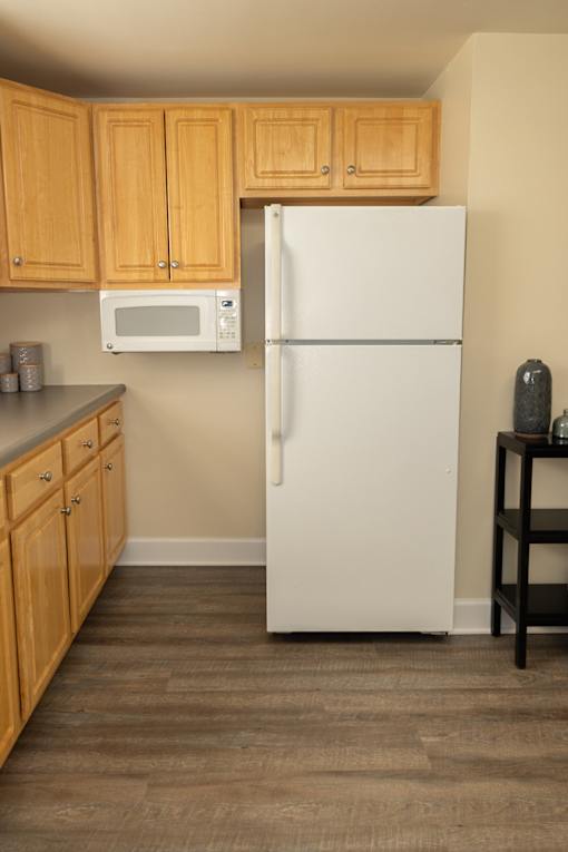 A white refrigerator in a kitchen with wooden cabinets.