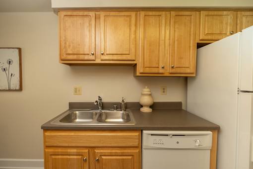 A kitchen with wooden cabinets and a white refrigerator.at Chapel Valley Townhomes, Maryland, 21236