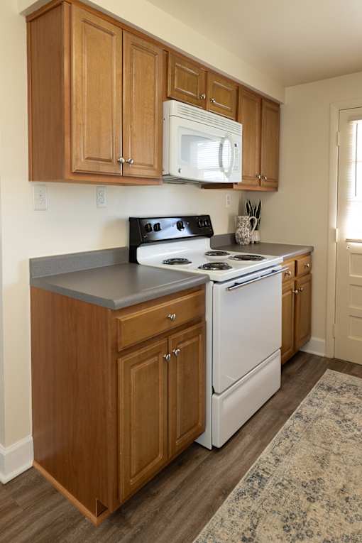 Wooden kitchen cabinets with white microwave and oven with gas range