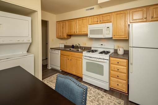 A kitchen with wooden cabinets and white appliances at The Brittany Apartments, Pikesville, MD