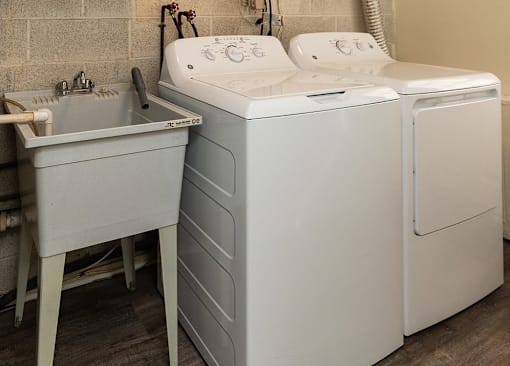 A white washing machine and sink in a laundry room at Kingston Townhomes, Baltimore, MD