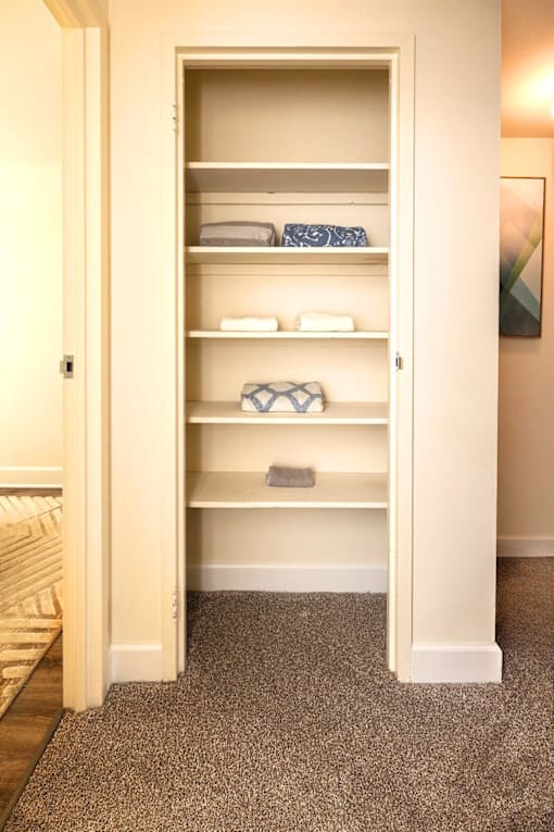 A white closet with shelves and towels at Kingston Townhomes, Baltimore, MD