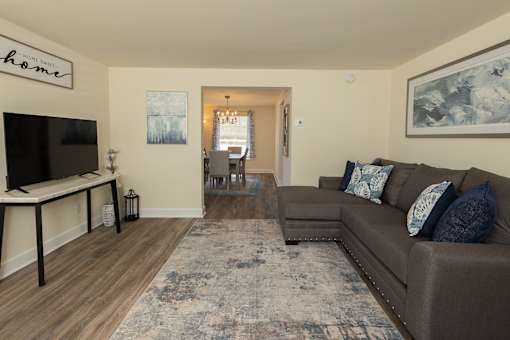 A living room with a brown couch and a television at Walnut Grove Townhomes* Apartments, Essex, MD