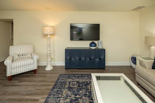 A living room with a chair, a sofa, a television, and a rug at The Brittany Apartments, Pikesville, MD