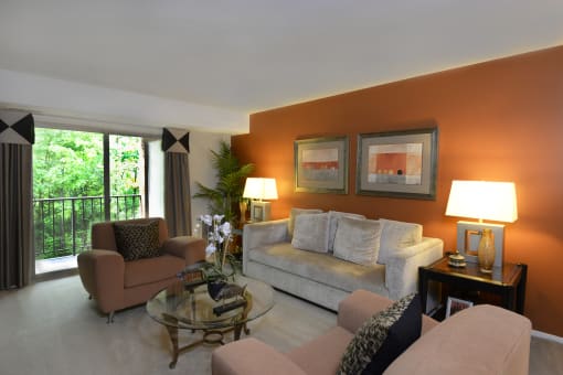 a living room with an orange accent wall and a gray couch at Liberty Gardens Apartments, Baltimore, MD 21244