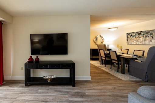 A black coffee table with a TV above it and a red vase on it.