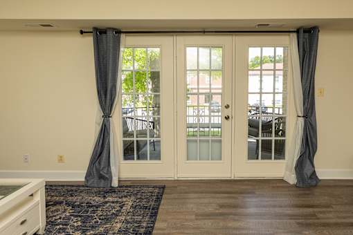 A room with a rug and a table with a white door and a window at The Brittany Apartments, Pikesville, MD, 21208