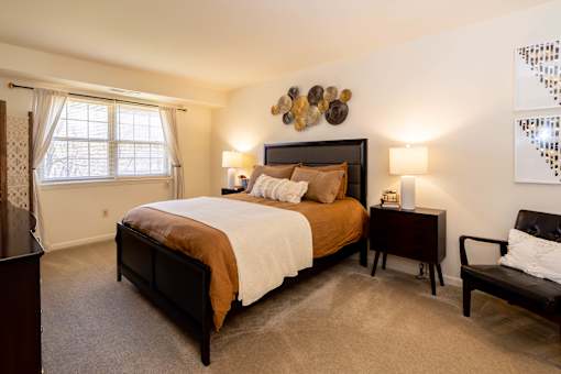 A bedroom with a large bed and a chair.