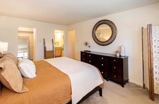 A bedroom with a bed, dresser, and mirror.