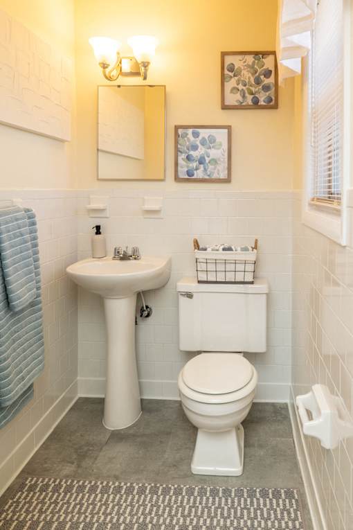 A bathroom with a toilet, sink, and mirror.