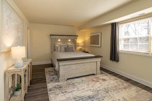 A bedroom with a bed, nightstand, and a rug.