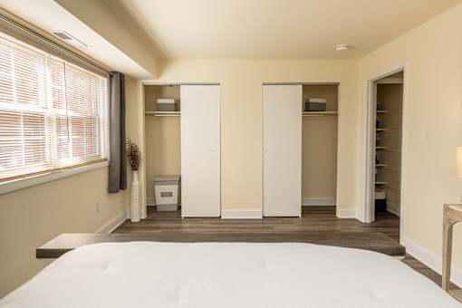A bedroom with a large bed and a window with blinds.