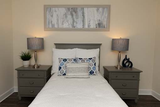 A bedroom with a bed, two nightstands, and a painting above the bed.