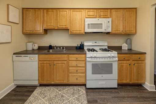 A kitchen with wooden cabinets and a white stove top oven.