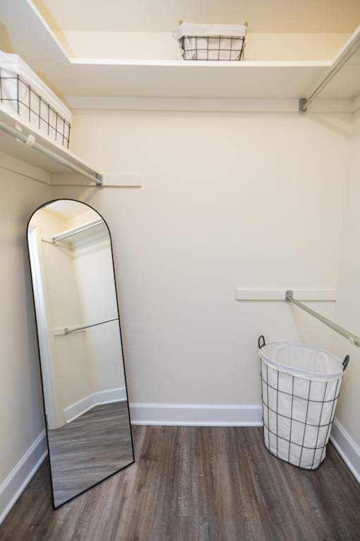 Walk-in closet with standing mirror and laundry basket